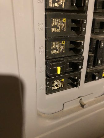 Close-up of a circuit breaker panel showing the labels and a partially flipped yellow switch on breaker 27.