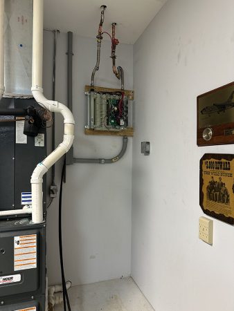 A gas furnace and water heater installed in a small utility room, showcasing their compact arrangement.