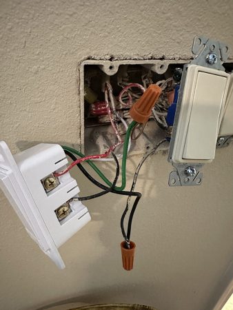 A white light switch next to a white light bulb, both set against a neutral background.