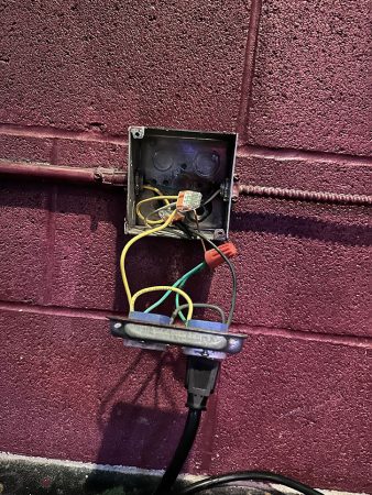 A wall featuring a box with wires connected to it, indicating possible electrical or communication equipment.