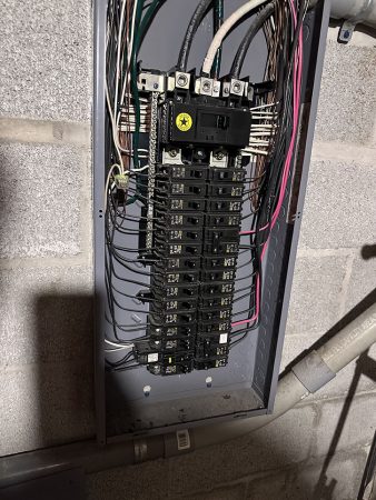 Panel containing wires and electrical equipment, showcasing a complex arrangement of components and connections.