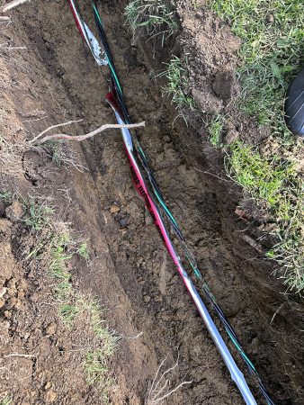 A hose connected to another hose that is buried in the ground, indicating a watering or drainage system.