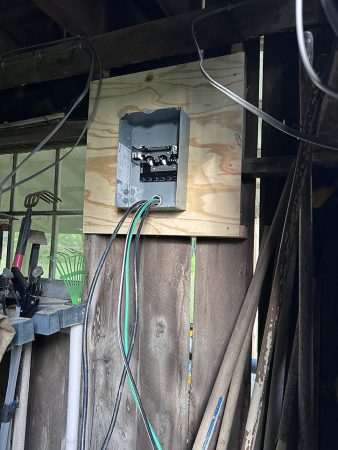 A wooden wall featuring a box and several wires connected to it.
