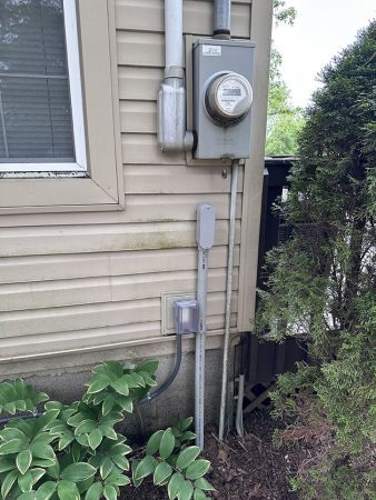 A water meter and a water heater positioned outside a residential house, showcasing utility equipment.