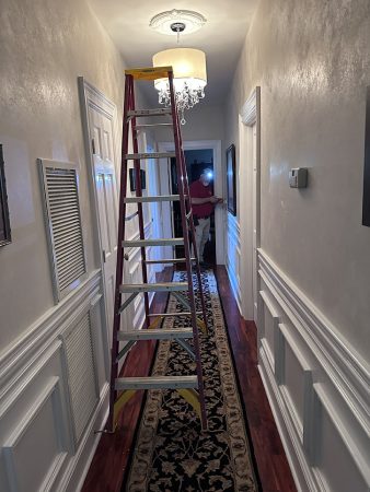 A ladder is mounted on the wall in a narrow hallway, providing access to higher areas.