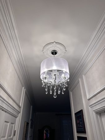 Chandelier elegantly hanging from the ceiling in a well-lit hallway, adding a touch of sophistication to the space.
