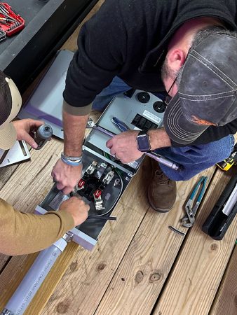 Two men collaborating on machinery, focused on adjusting and maintaining the equipment for optimal performance.