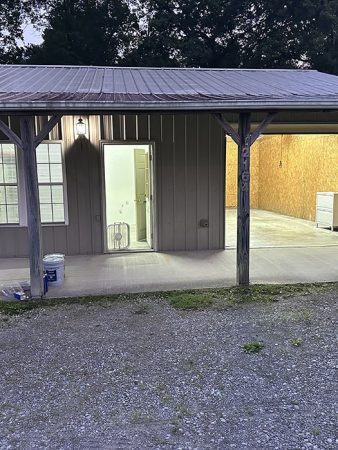 A small garage with a truck parked in front, surrounded by a grassy area and a clear blue sky.
