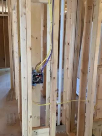 A room featuring exposed wood framing and visible electrical wires along the walls and ceiling.