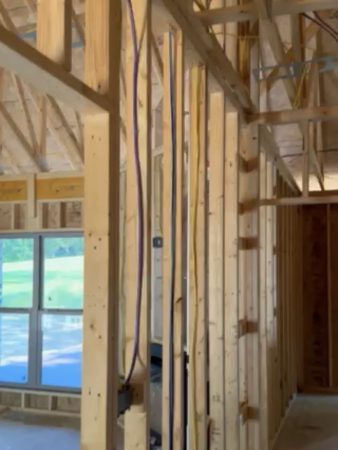 A construction site showing a room with wooden framing and windows being installed.