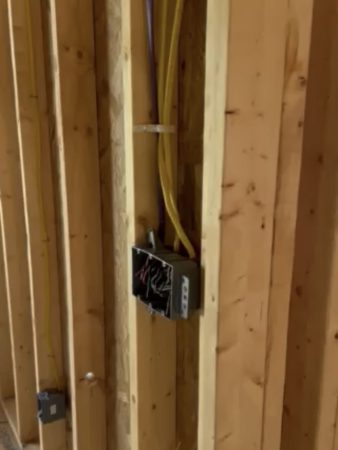 A wall displaying exposed electrical wires and cables, illustrating the inner workings of the electrical system.