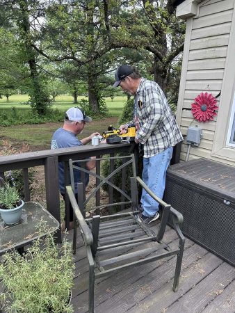 Two men constructing a wooden deck, focused on their tasks with tools and materials around them.