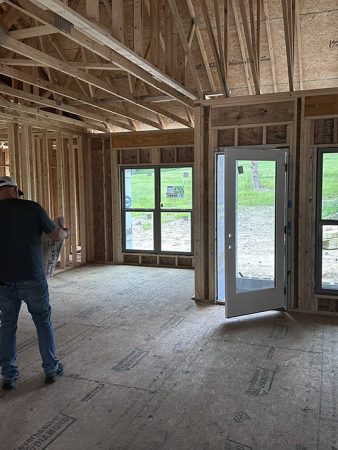 Two men standing in a room with wooden framing, engaged in conversation.