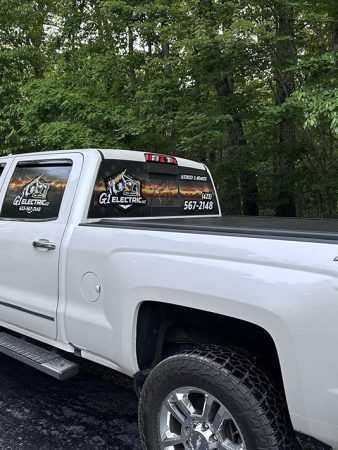 A white truck parked in a parking lot, surrounded by other vehicles and marked parking spaces.
