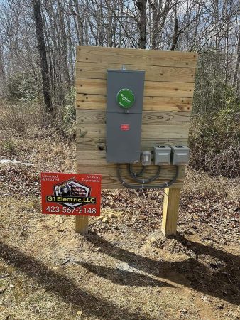 Electrical service panel on a wooden post, accompanied by a sign for G1 Electric, LLC, showcasing professionalism in a wooded area.