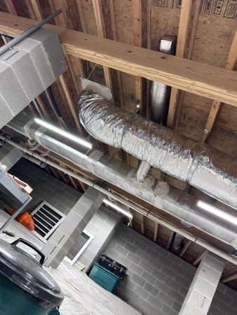 A room featuring exposed pipes and ductwork along the walls and ceiling, indicating a mechanical or industrial setting.